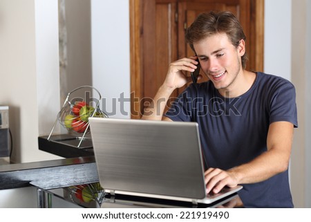 Entrepreneur man on the phone working with a laptop in the kitchen at home
