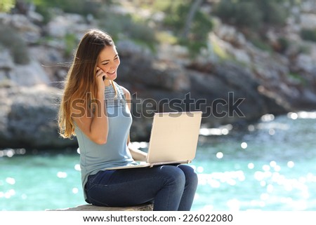 Freelance woman working in vacation on the phone on the beach with the sea in the background
