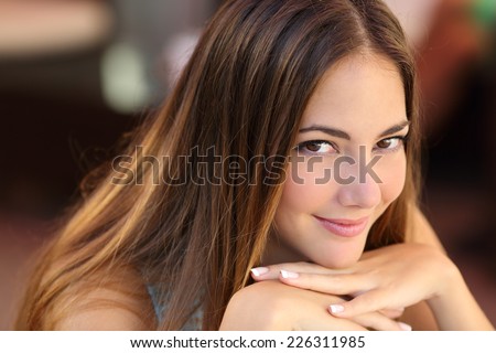 Portrait of a confident woman with smooth skin looking at camera with an unfocused background
