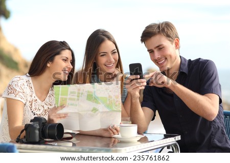 Group of young tourist friends consulting gps map in a smart phone in a restaurant with the beach in the background