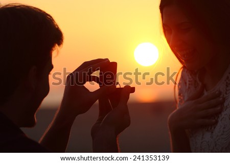 Back light of a couple proposal of marriage on the beach at sunset