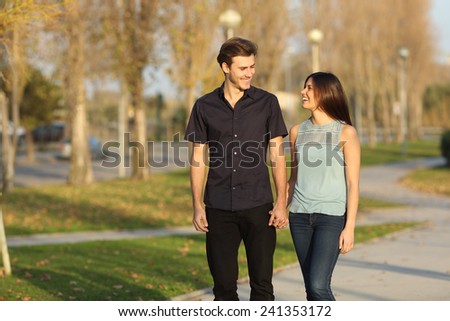 Happy couple laughing while taking a walk in a park