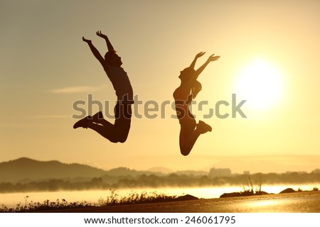 Fitness couple jumping happy at sunset with the sun in the background