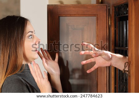 Aggression when a burglar try to attack a housewife with a hand through the door at home