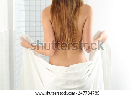 Back view of a woman body entering in the shower with a white towel