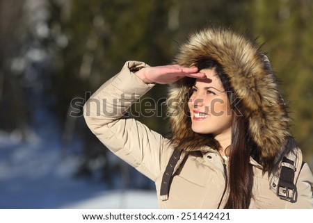 Woman looking forward with the hand on forehead in a forest in winter holidays