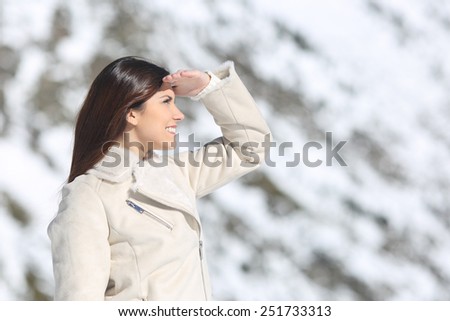 Woman looking forward with the hand on forehead in winter holidays with a snowy mountain in the background