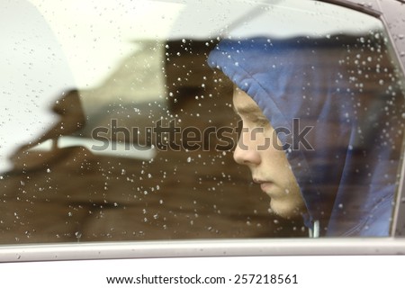 Sad teenager boy worried inside a car looking through the window