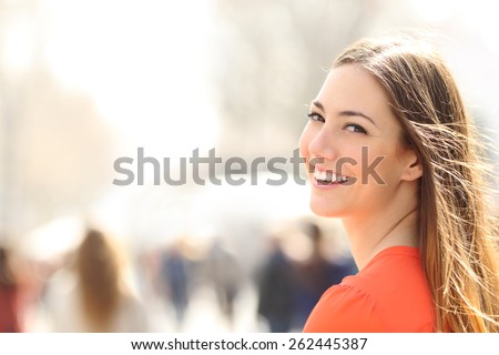 Beauty woman with perfect smile and white teeth walking on the street and looking at camera