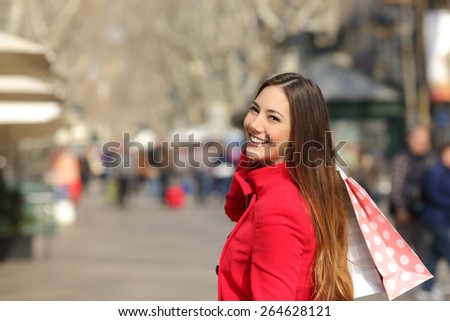 Happy shopper woman walking and shopping in the street in winter holding bags