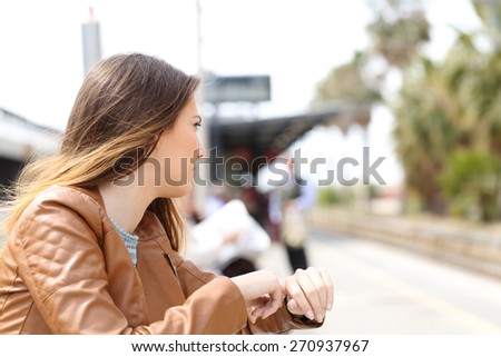 Angry girl waiting in a train station and looking to railway