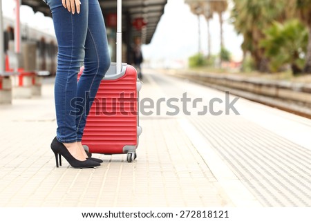 Casual traveler tourist legs waiting in a train station with a suitcase