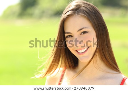 Candid woman with perfect teeth and smile looking you with the wind moving her hair