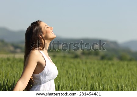 Girl breathing fresh air with white dress in a green wheat meadow