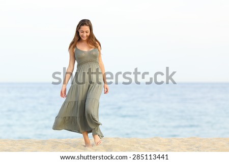 Candid feminine longing girl walking enjoying carefree on the sand of the beach towards camera