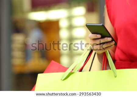 Shopper woman hand shopping with a smart phone and carrying bags