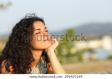 Woman relaxing and enjoying the sun in a warmth park at sunset