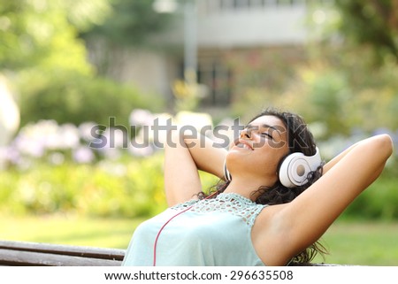 Woman listening to music with headphones and relaxing in a park