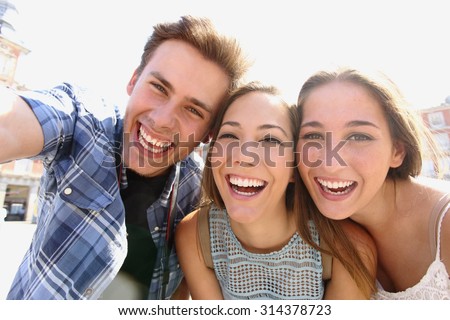 Group of happy teen friends laughing and taking a selfie in the street