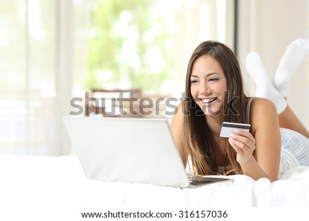 Shopper shopping online with credit card and laptop on the bed at home