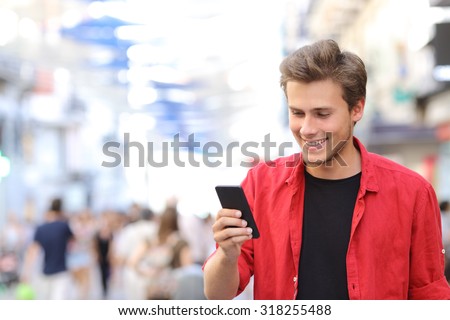 Happy man in red texting on a mobile phone in the street