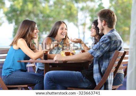 Group of four friends talking and drinking sitting in a terrace at home