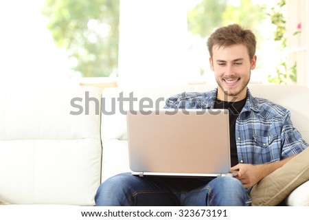 Front view of a handsome man using a laptop sitting on couch at home