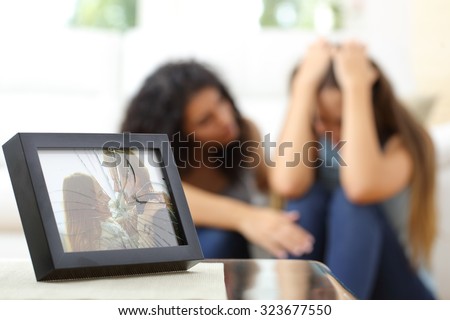 Sad wife after a breakup with a friend comforting her in the living room