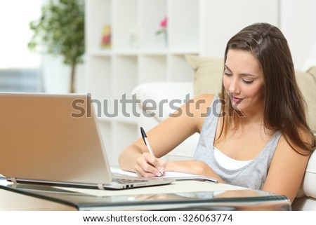 Entrepreneur or student working or studying at home and writing notes sitting on the floor at home