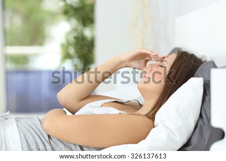 Profile of a woman suffering head ache lying on the bed at home