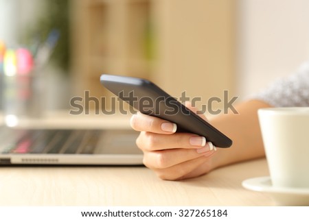 Close up of a woman hand using a smart phone on a desk at home