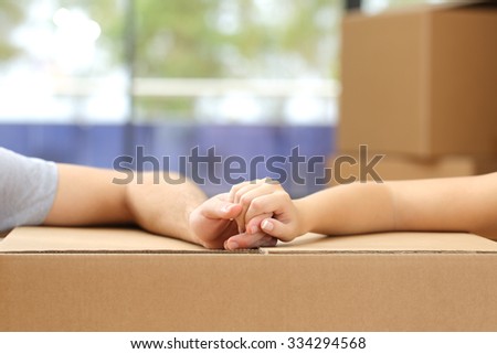 Close up of a couple holding hands over a carton box and moving home