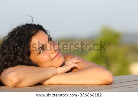 Candid girl dreaming and thinking leaning on a table outdoors