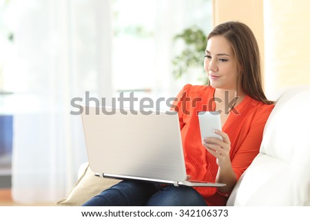 Entrepreneur woman working with a laptop and mobile phone sitting on a couch at home