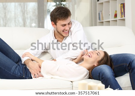 Playful couple or marriage tickling and laughing in a couch at home