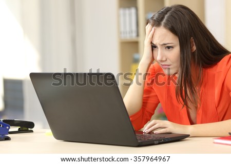 Sad and worried entrepreneur working on line with a laptop in an office desk or home
