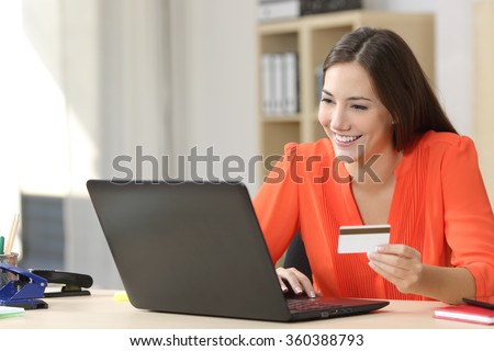 Entrepreneur buying online with a credit card and a laptop in a desk at home or a little office
