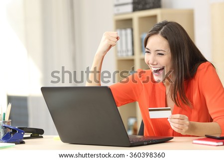 Euphoric shopper buying on line with a laptop and a credit card at home or office