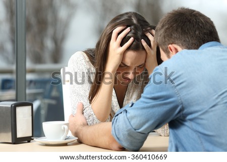 Male comforting to a sad depressed female who needs help in a coffee shop. Break up or best friend concept
