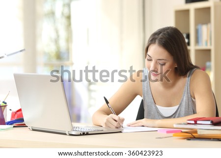 Beautiful student studying on line and learning writing notes in a desk at home