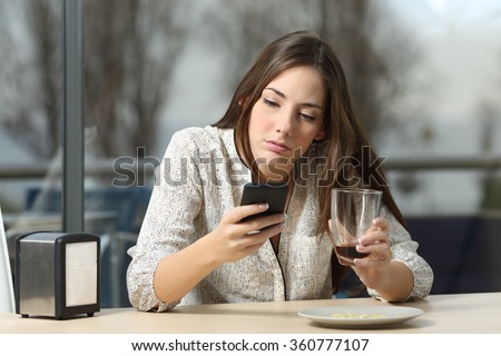 Angry woman stood up in a date in a coffee shop searching for messages and lost calls in a smart phone
