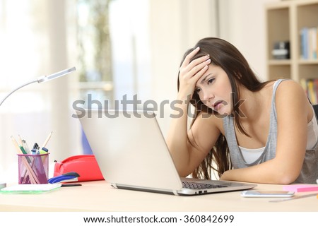Worried and sad student female searching information in a laptop on line in a desk at home room