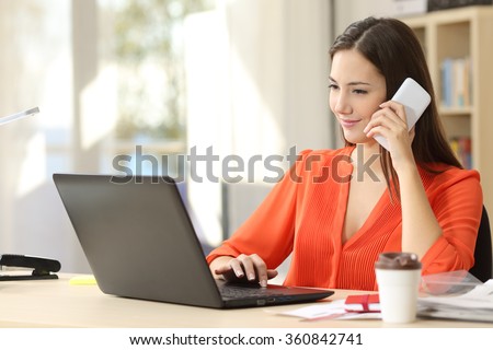 Beautiful freelancer female working on line and talking on the phone and browsing in a laptop at home or office