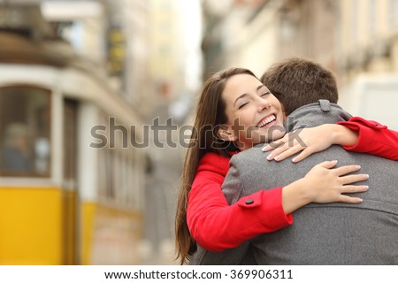 Encounter of a happy couple hugging in love in the street after a tram travel in a colorful scenery