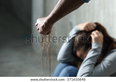 Domestic violence with a man hurting to a terrified woman pulling hair and holding it in the fist in a dark place