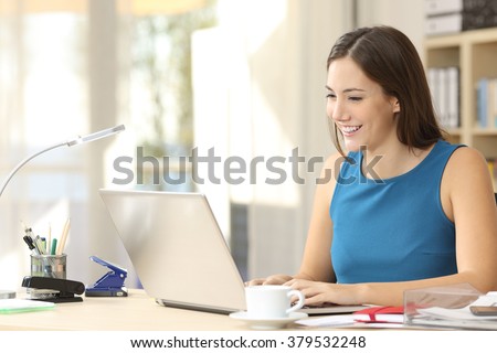Happy casual entrepreneur working on line typing with a laptop at office with a window in the background