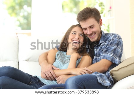 Happy couple or marriage hugging and enjoying in a couch at home