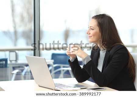 Portrait of a pensive businesswoman wearing suit thinking and planning looking outdoors through the window in a bar with the horizon in the background