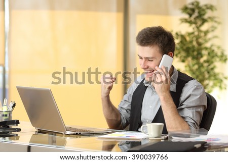 Excited businessman talking on the mobile phone while is watching business content in a laptop