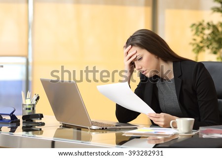 Worried businesswoman reading a notification while is working sitting in a desk at office